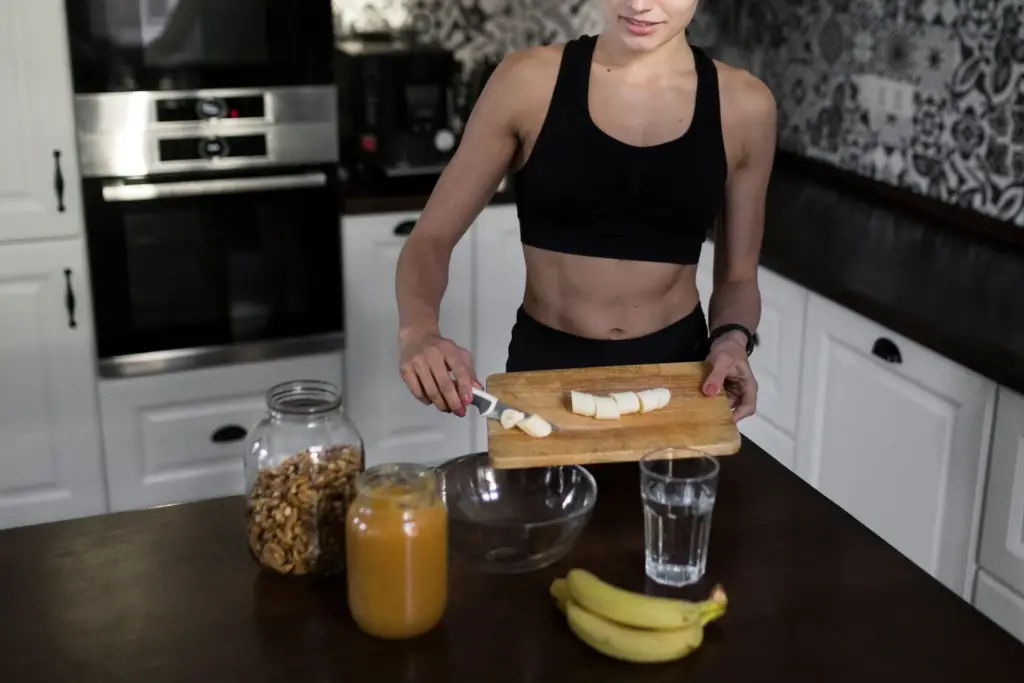 Woman preparing a healthy snack with bananas and nuts in a modern kitchen, promoting home workouts nutrition.