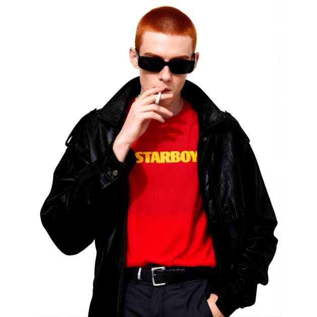 A male model with red hair, sunglasses, and a black leather jacket, wearing the red 